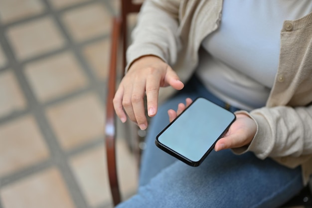 Draufsicht einer asiatischen Frau, die ihr Smartphone benutzt, während sie sich im Freien entspannt