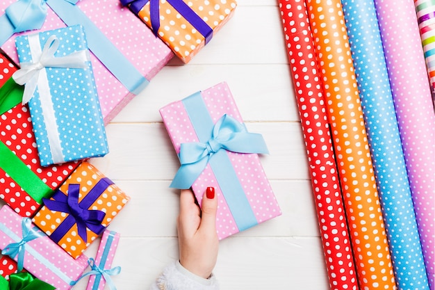 Draufsicht einer Frau, die eine Geschenkbox in ihren Händen auf festlichem hölzernem Hintergrund hält