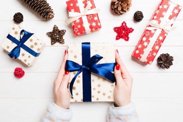 Draufsicht einer Frau, die eine Geschenkbox in ihren Händen auf festlicher Holzoberfläche hält