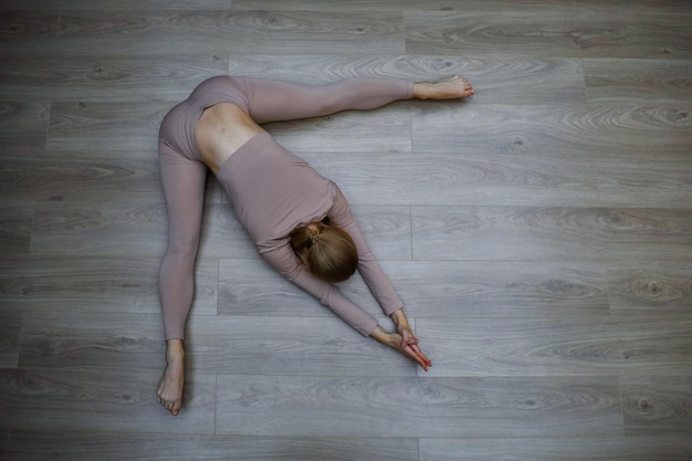 Draufsicht einer Frau, die Entspannungsübungen auf Holzboden macht.