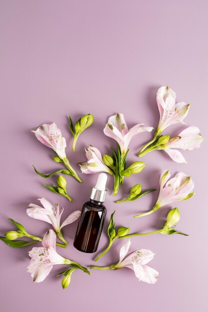 Draufsicht einer Glasflasche mit kosmetischem Blumenölserum für die Hautpflege von Gesicht und Körper Fliederhintergrund frische Blumen