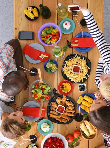 Foto draufsicht einer gruppe von menschen, die zusammen zu abend essen, während sie am holztisch sitzen essen auf dem tisch die leute essen fast food