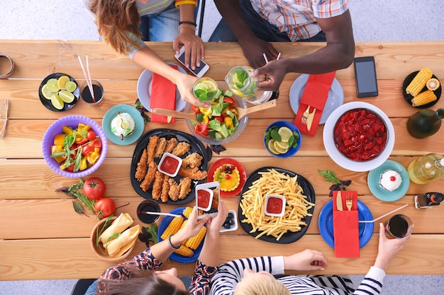 Foto draufsicht einer gruppe von menschen, die zusammen zu abend essen, während sie am holztisch sitzen essen auf dem tisch die leute essen fast food