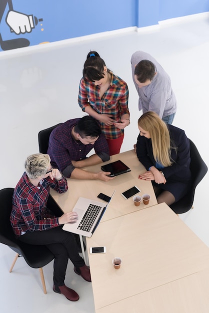 Draufsicht einer multiethnischen Gruppe von Startup-Geschäftsleuten beim Brainstorming-Treffen in einem modernen, hellen Bürointerieur