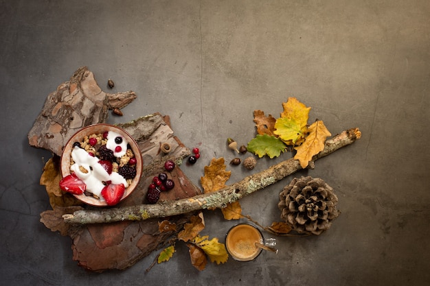 Draufsicht eines gesunden Frühstücks mit Müsli, Joghurt und saisonalen Beeren auf einem konkreten Hintergrund