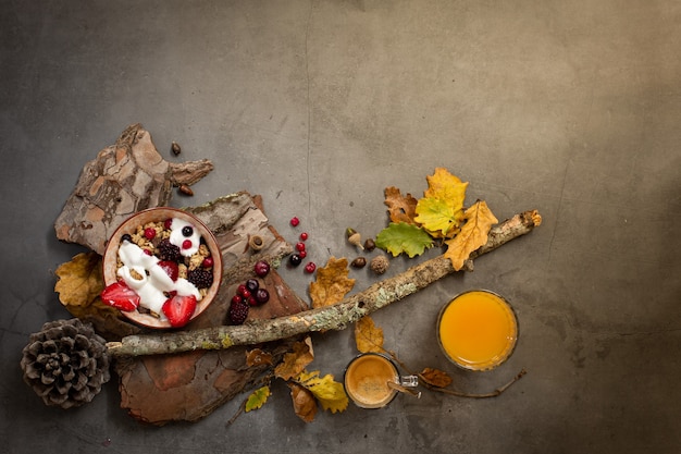 Draufsicht eines gesunden Frühstücks mit Müsli, Joghurt und saisonalen Beeren auf einem konkreten Hintergrund