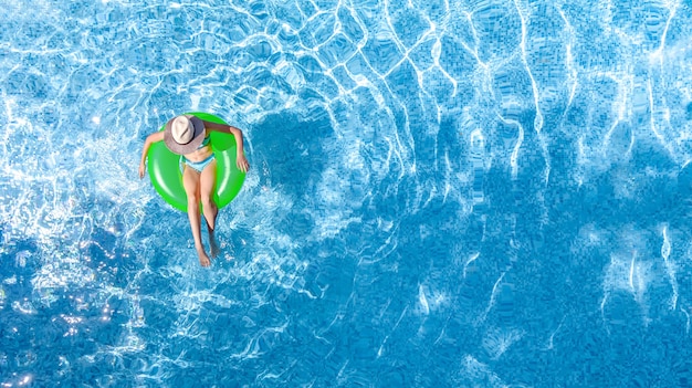 Draufsicht eines jungen Mädchens in einem grünen aufblasbaren Ring auf einem Swimmingpool on
