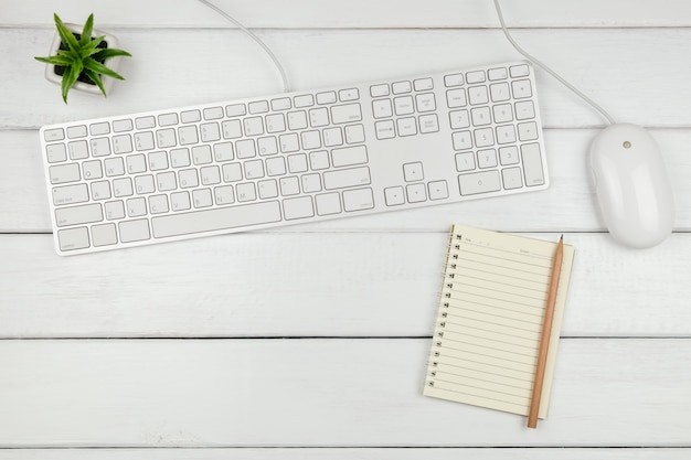 Foto draufsicht eines notizbuchs mit tastatur und maus auf weißem schreibtisch