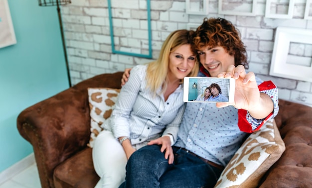 Draufsicht eines Paares, das ein Selfie auf einem Sofa in einem Café macht Selektiver Fokus auf Smartphone