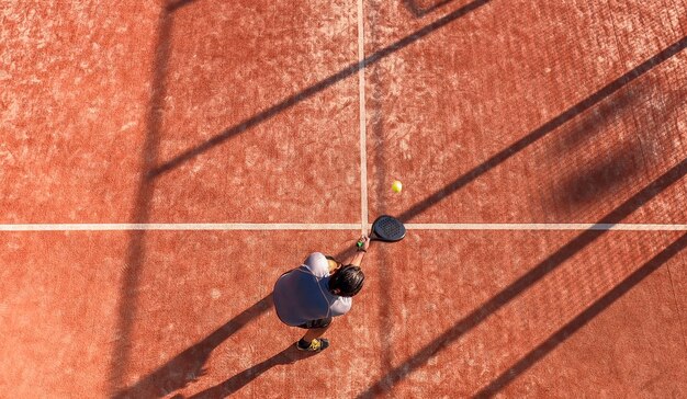 Draufsicht eines Paddle-Tennisspielers, der den Ball auf einem Außenplatz schlägt. Sporttraining oder Paddelspiel.