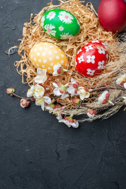 Draufsicht farbig gestaltete Eier auf Stroh dunklem Hintergrund Novruz Frühling verzierte bunte horizontale Urlaubskonzept