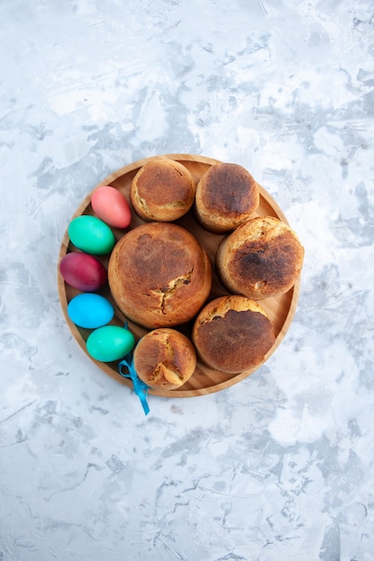 Draufsicht farbige Ostereier mit Feiertagsbrot und -kuchen im Fach auf weißer Oberfläche