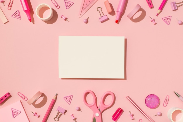 Draufsicht Foto von Schulzubehör rosa Briefpapier und weißer Karte in der Mitte auf isoliertem pastellrosa Hintergrund mit Leerzeichen