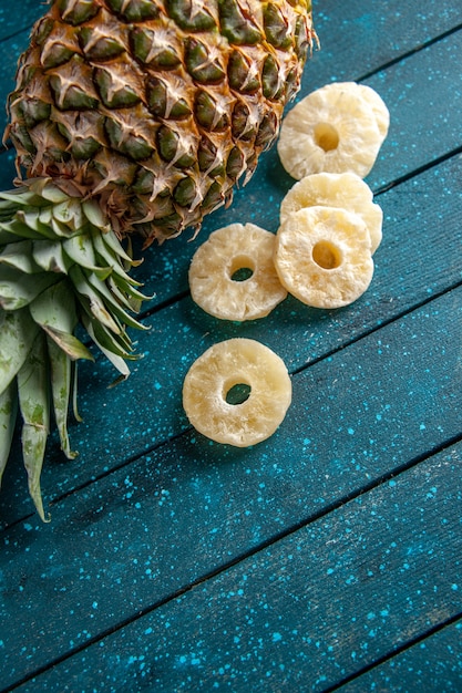 Draufsicht frische ananas, die getrocknete ananasringe auf blauem hintergrund niederlegt