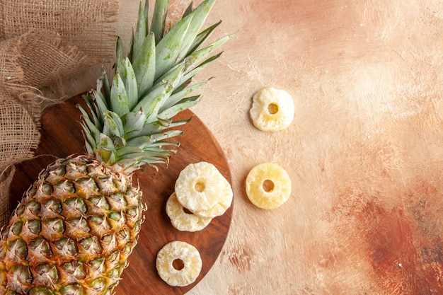 Draufsicht frische Ananas zur Festlegung auf Holzbrett trockene Ananasscheiben auf beigem Hintergrund