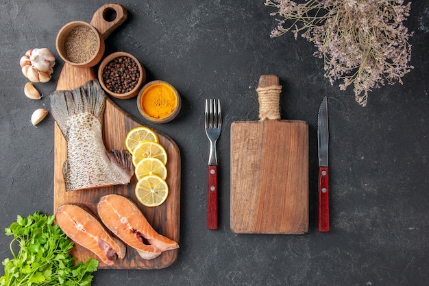 Draufsicht frische Fischscheiben mit Zitrone und Gewürzen auf dunkelgrauem Hintergrund Fischsalat Wasser Fleisch Ozean Meer Mahlzeit Abendessen Meeresfrüchte