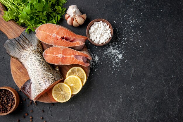 Draufsicht frischer Fisch mit Zitronenscheiben auf dunklem Hintergrund Ozean Meeresfrüchte Mahlzeit Essen Mahlzeit Wasser Salat Meer Fisch Fleisch