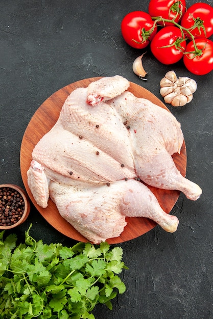 Draufsicht frisches rohes Huhn mit Tomatengrün und Gewürzen tomatoes