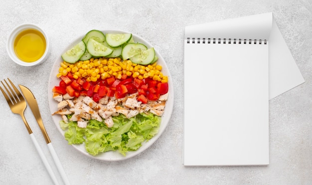 Draufsicht Gemüsesalat mit Huhn und Öl mit leerem Notenook