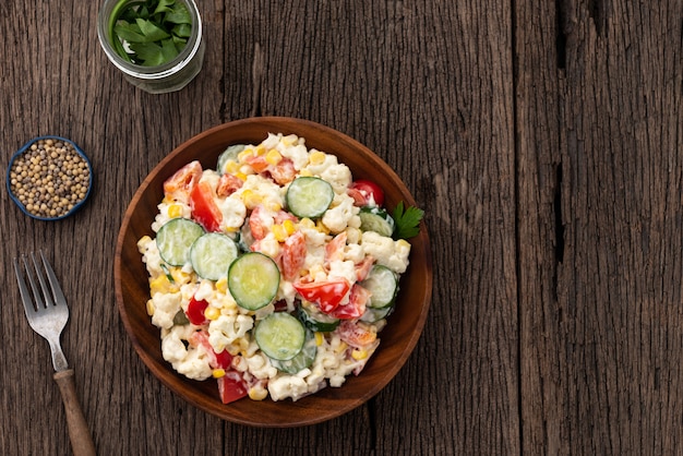 Foto draufsicht gurkengemüsesalat im hölzernen tellerlebensmittelhintergrund