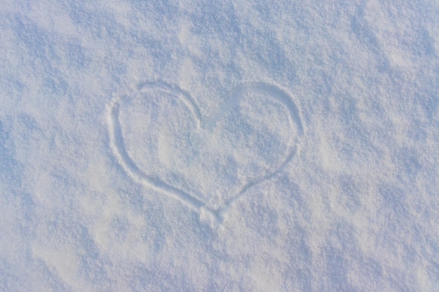 Draufsicht handgezeichnet eine Herzform auf natürlicher, reinweißer, weicher Schneeoberfläche an einem kalten Wettertag Symbol der Liebe in der Winterferienzeit