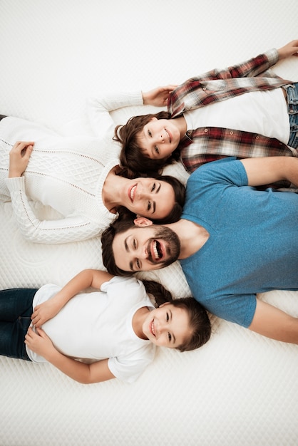 Draufsicht junge glückliche Familie, die auf Matratze liegt