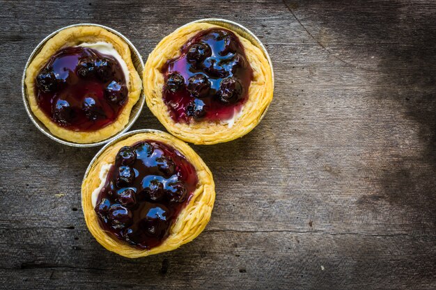 Draufsicht-Käsekuchen-Torte mit Blaubeermarmelade auf Grunge-Holztisch