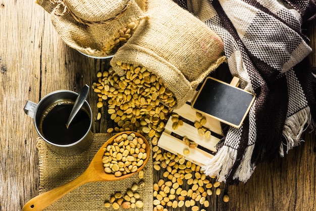 Draufsicht Kaffeebohnen und Kaffeetasse auf einem Holztisch.