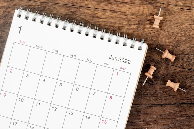 Draufsicht Kalendertisch 2022 im Januar-Monat, das Konzept der Planung und Frist mit Push-Pin auf Holztischhintergrund. Geschäftsplanungstermin-Meeting-Konzept