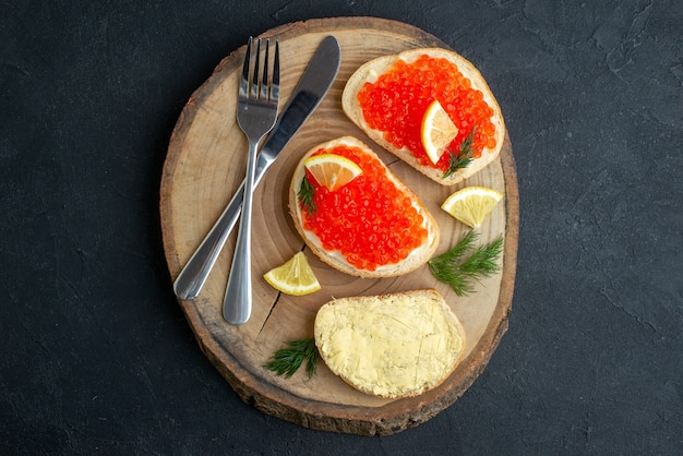 Draufsicht Kaviar-Sandwiches mit Besteck auf dunkler Oberfläche des Schneidebretts