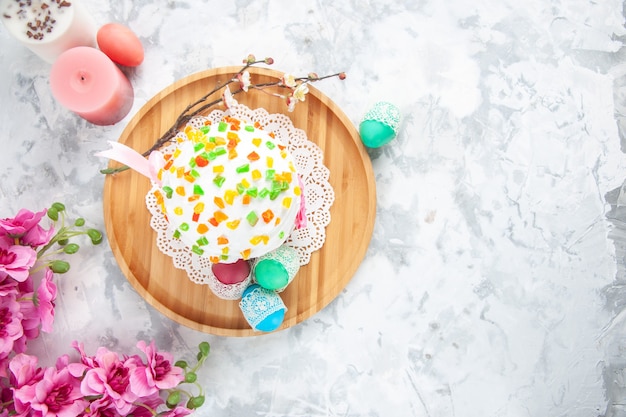 Draufsicht köstlicher Osterkuchen mit getrockneten Früchten und farbigen Eiern auf weißer Oberfläche