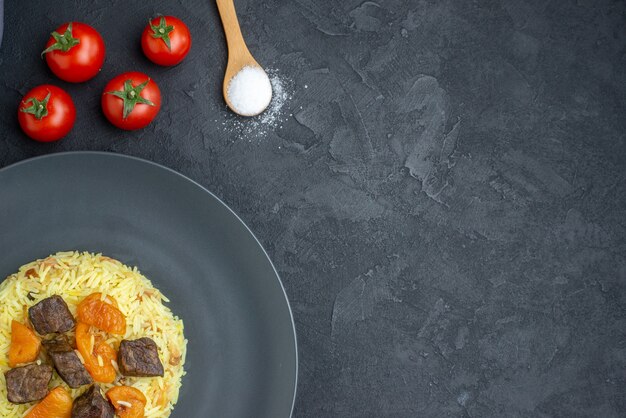 Draufsicht köstlicher Pilaw gekochter Reis mit Fleischscheiben und Tomaten auf dunkler Oberfläche