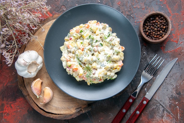 Draufsicht köstlicher russischer salat mit besteck auf dunkler oberfläche