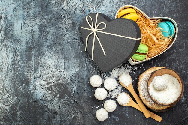 Draufsicht Kokosbonbons mit französischen Macarons auf grauem Hintergrund Kuchen Weihnachtsgeschenk rotes Liebespaar Valentinstag süße Goodie Farbe