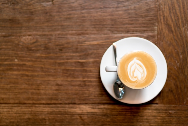 Draufsicht Lattekunstkaffee auf hölzernem. Herzform Latte Art Schaum.