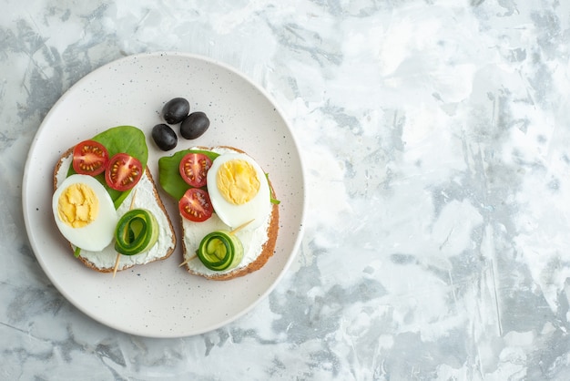 Draufsicht leckere Ei-Sandwiches mit Tomaten in der Platte weiße Oberfläche Hintergrund Mittagessen Sandwich Essen Brot Burger Gesundheit Diät Mahlzeit