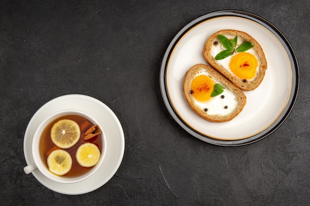 Draufsicht leckere Eiertoasts mit Tasse Tee auf dunklem Hintergrund Mahlzeit Brot Omelette Essen Mittagessen Morgen Frühstück Tee