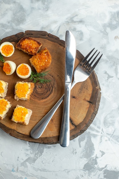 Draufsicht leckere Kaviar-Sandwiches mit gekochten Eiern und Besteck auf Holzbrett weißer Oberfläche Essen Frühstück Meeresfrüchte Fisch Toast Essen