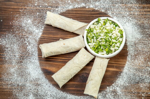 Draufsicht leckere Pitas mit Grün um Mehl auf braunem Tisch