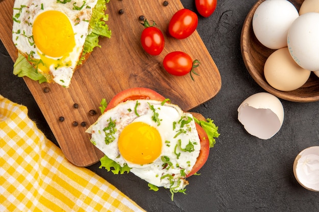 Draufsicht leckere Sandwiches mit Ei und Tomaten auf dunklem Hintergrund Ei Frühstück Brot Mittagessen Kochen Omelett Essen