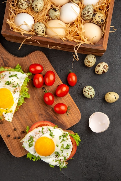 Draufsicht leckere Sandwiches mit Eiern und Tomaten auf dunklem Hintergrund Mahlzeit Ei Frühstück Brot Mittagessen Essen Omelette kochen