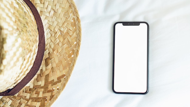 Draufsicht leerer Bildschirm von Smartphone auf Raum und Hut, während der Freizeit.