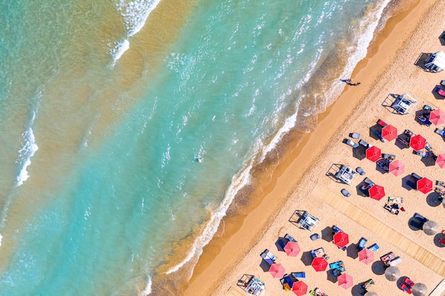 Draufsicht Luftdrohnenfoto des Bananenstrandes mit wunderschönen türkisfarbenen Meereswellen und roten Sonnenschirmen Urlaubsreisen Hintergrund Ionisches Meer Insel Zakynthos Griechenland