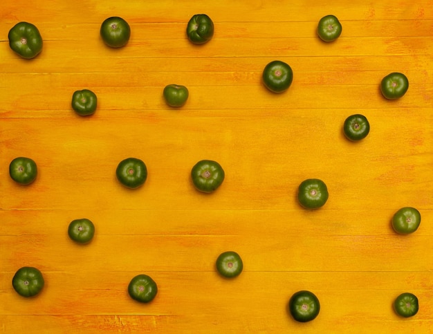 Draufsicht mexikanisches grünes Tomatenmuster über gelbem Tabellenhintergrund