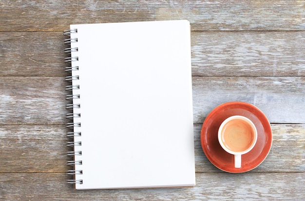 Draufsicht mit Kaffeetasse und Notizbüchern auf Holztisch im Büro