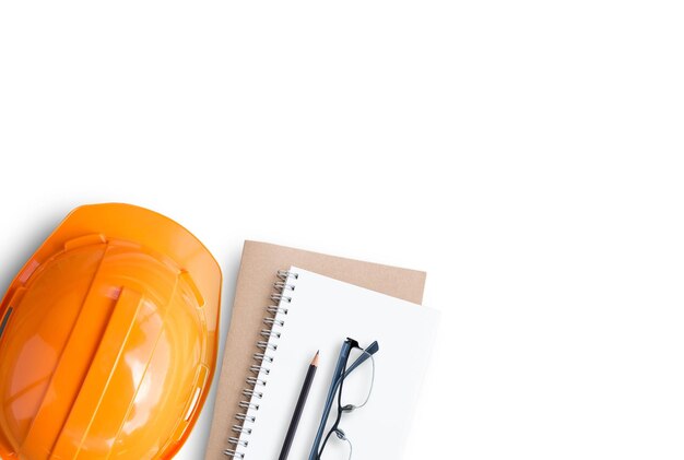 Draufsicht mit orangefarbenem Sicherheitshelm und leerem Notizbuch