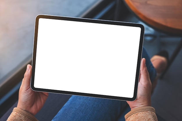 Draufsicht-Mockup-Bild einer Frau, die ein digitales Tablet mit einem leeren weißen Desktop-Bildschirm hält