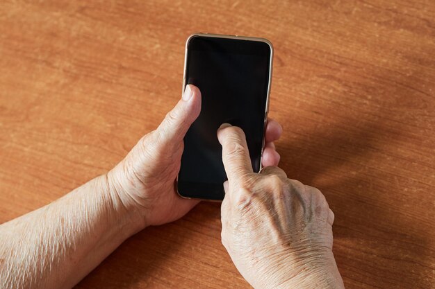 Draufsicht Nahaufnahme der Hand der alten Frau, die auf dem Smartphone tippt