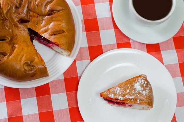 Draufsicht nahaufnahme foto von kirschtorte und tasse tee auf karierter tischdecke