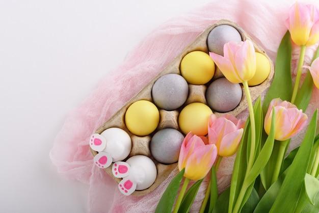 Draufsicht Ostern Zusammensetzung von Eiern, Tulpen und Kaninchenpfoten in Pappkarton auf weißem Hintergrund